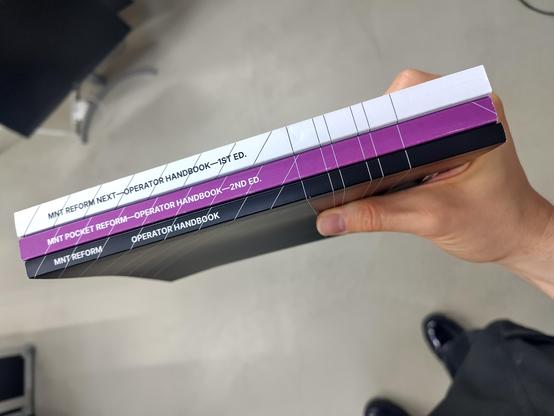 black, purple and white mnt operator manuals in a stack