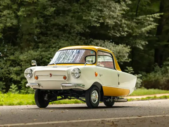 A tiny white and yellow micro car with chrome numbers and wing mirrors