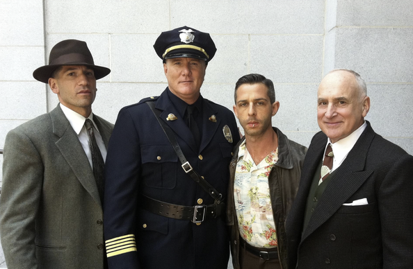 Some of the main caste of Mob City posing for a photograph. McGrady in character as Clemence B Horrall is in full uniform in the middle.